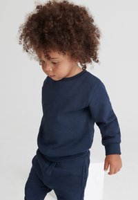 Felpa blu navy e pantaloni abbinati realizzati in morbido tessuto. Polsini e vita a costine, con un design semplice privo di fantasie.