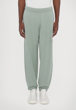Pantalons de survêtement vert clair avec une taille élastique, des chevilles resserrées et des poches latérales. Design simple avec un logo discret sur la cuisse.