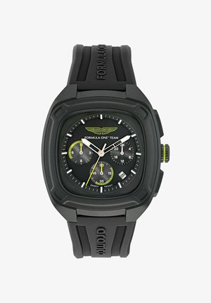 Schwarze Gummi-Uhr mit quadratischem Ziffernblatt, ausgestattet mit einem schwarzen Ziffernblatt, weißen und gelben Akzenten sowie Subziffern. Text "Formel Eins Team" sichtbar.