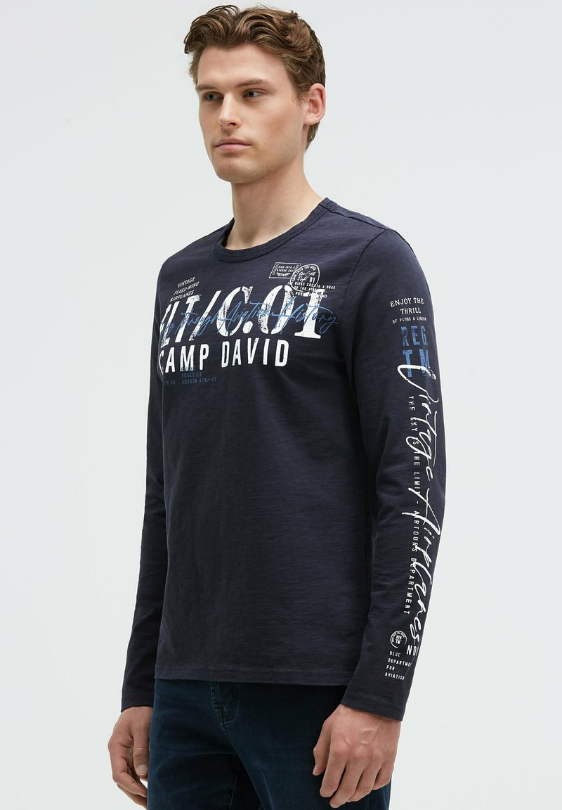 Langärmliges, navyfarbenes Hemd aus Baumwolle; mit grafischem Druck und Text auf der Vorderseite und dem Ärmel; runder Halsausschnitt; lässige Passform.