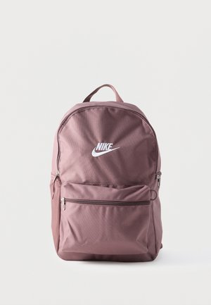 Fioletowy plecak Nike z przednią kieszenią na zamek, górnym uchwytem i białym logo Nike na jednolitym tle.