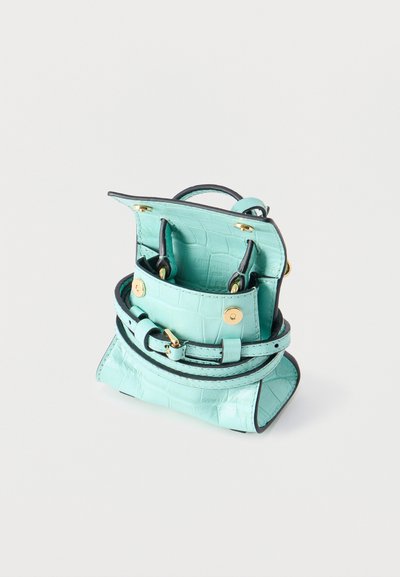 Μικρό τιρκουάζ τσαντάκι με υφή κροκοδείλου, μαύρες άκρες, χρυσά κλεισίματα με κουμπώματα και λεπτό ιμάντα ζώνης, εμφανιζόμενο ανοιχτό σε φωτεινό φόντο.