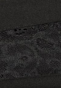 Tecido preto com uma sobreposição de renda com um padrão floral. A textura é suave e ligeiramente brilhante, contrastando com uma base mate.