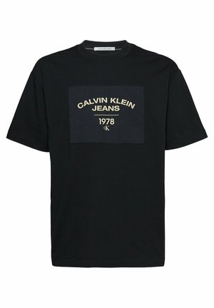 T-shirt noir à manches courtes avec le texte "Calvin Klein Jeans 1978" et un petit logo "CK" sur un patch carré sur la poitrine.