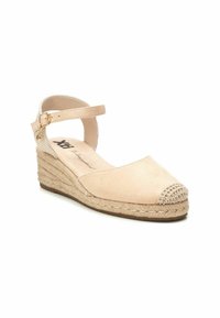 Sandalia de cuña de ante beige con punta redonda, media suela de yute trenzado y tira de tobillo con hebilla dorada. Detalle en la puntera texturizada.