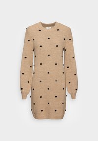 Robe en maille beige à pois noirs. Elle présente un col rond, des manches longues et des poignets côtelés pour ajouter de la texture.