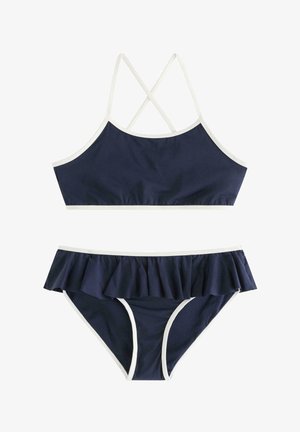 Tummansininen kaksiosainen uimapuku, jossa on valkoiset reunukset, ristikkäiset olkaimet ja röyhelöidyt bikinihousut.