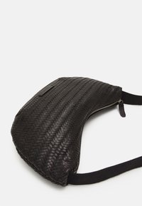 Borsa nera in pelle intrecciata con forma curva, dotata di chiusura a zip e tracolla in tessuto. Superficie testurizzata con una finitura elegante.