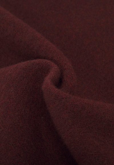 Burgundijas vilnas audums ar mīkstu, pūkainu tekstūru, kas izceļas ar gludu kritumu un bagātām krāsu variācijām visā audumā. Nav redzami nekādi raksti vai aksesuāri.