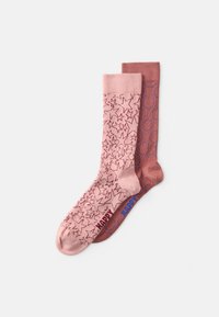 Calcetines rosas con un patrón de estrellas en la izquierda y un color sólido con acentos circulares en la derecha, ambos con puños acanalados y una marca de contraste.