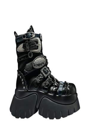 Crna platforma čizma s debelim rebrastim potplatom, višestrukim teksturiranim trakama te ukrasnim srebrnim kopčama i metalnim ukrasima.