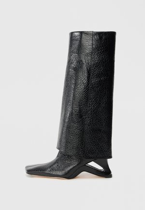 Fekete bőr csizma texturált felülettel, szögletes vágással, hegyes orral és egyedi sarokdizájnnal. Sima felületű, középvádli hosszúságú.