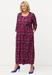 Buntes langes Kleid mit lebhaften geometrischen Mustern in Pink, Lila und Creme, mit Dreiviertelärmeln und seitlichen Taschen.