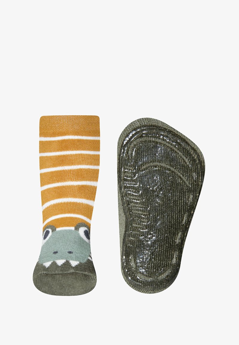 Gestreifte orange-weiße Socken mit einem grünen Dinosauriergesicht-Design und einer strukturierten, grünen Gummisohle für besseren Halt.