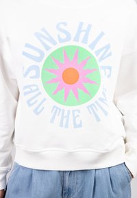 White sweatshirt featuring a colorful sun graphic in pink, green, and orange with the text "SUNSHINE ALL THE TIME" in light blue.