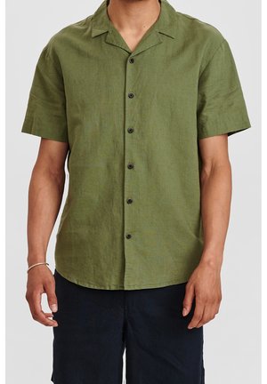 Camisa de botones de manga corta de color verde, hecha de un tejido texturizado, con un collar puntiagudo y seis botones negros en el frente.