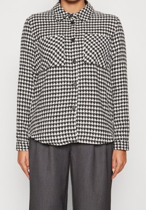Czarna i biała kurtka z wzorem houndstooth, z kołnierzem, dwiema kieszeniami na piersi i zapięciem na guziki, wykonana z teksturowanej tkaniny.
