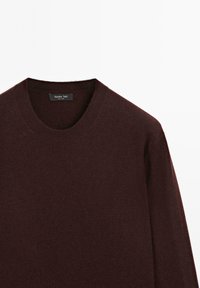Maglione borgogna a maglia con scollatura rotonda e maniche lunghe. Realizzato in tessuto morbido, presenta una leggera texture. Etichetta visibile all'interno della scollatura.