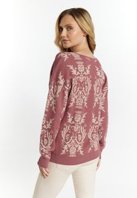 Maglione rosa a maglia con motivi floreali bianchi, vestibilità rilassata, scollatura ampia e polsini a coste. Tessuto morbido, vista posteriore mostrata.