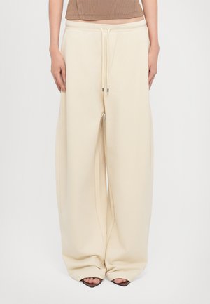 Beige wide-leg sweatpants with a drawstring waist, made from soft fabric, featuring a smooth texture and wide cuffs at the hem.