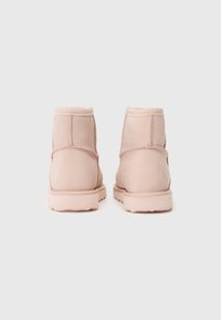 Pink suede ankle boots with a smooth texture, rounded toe, and reinforced heel. Features tonal stitching and a rubber sole.