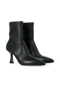 Une paire de bottines élégantes en cuir noir avec des embouts pointus et des talons kitten sculptés sur un fond blanc.