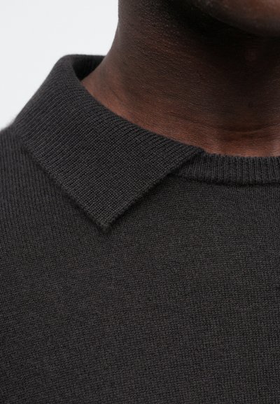 Ciemnoszary sweter dzianinowy o fakturowanej powierzchni, z płaskim kołnierzem i zbliżeniowym ujęciem tkaniny oraz dekoltu.