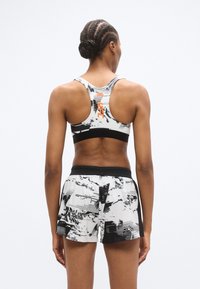 Fekete-fehér absztrakt mintával díszített sportmelltartó és rövidnadrág szett, légáteresztő anyagból készült, testhez simuló kivitelben, texturált derékrésszel.