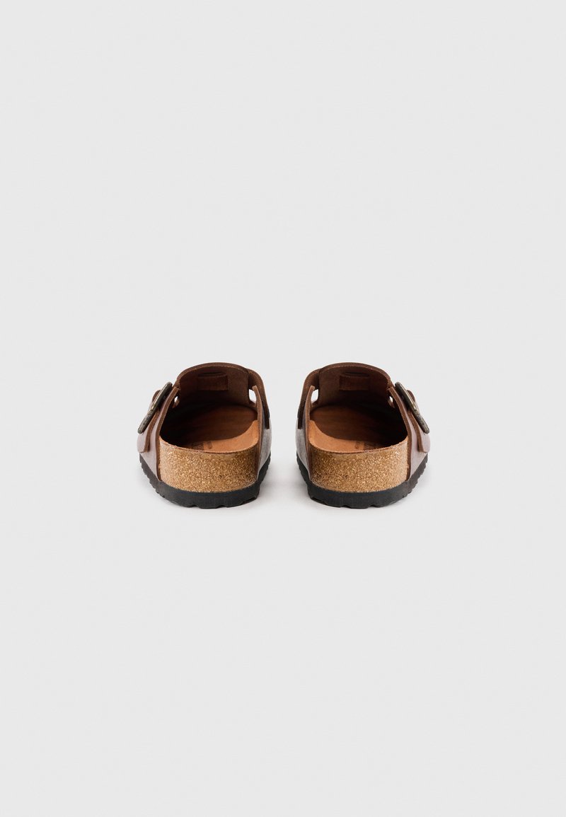Braune Ledersandalen mit Korkfußbett, offenem Rücken und verstellbarem Riemen. Texturierte Sohlen bieten Grip und Unterstützung. Einfaches Design.