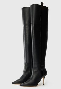Knee-high black leather boots with pointed toes, stiletto heels, and glossy accents near the top, featuring a sleek, smooth texture.