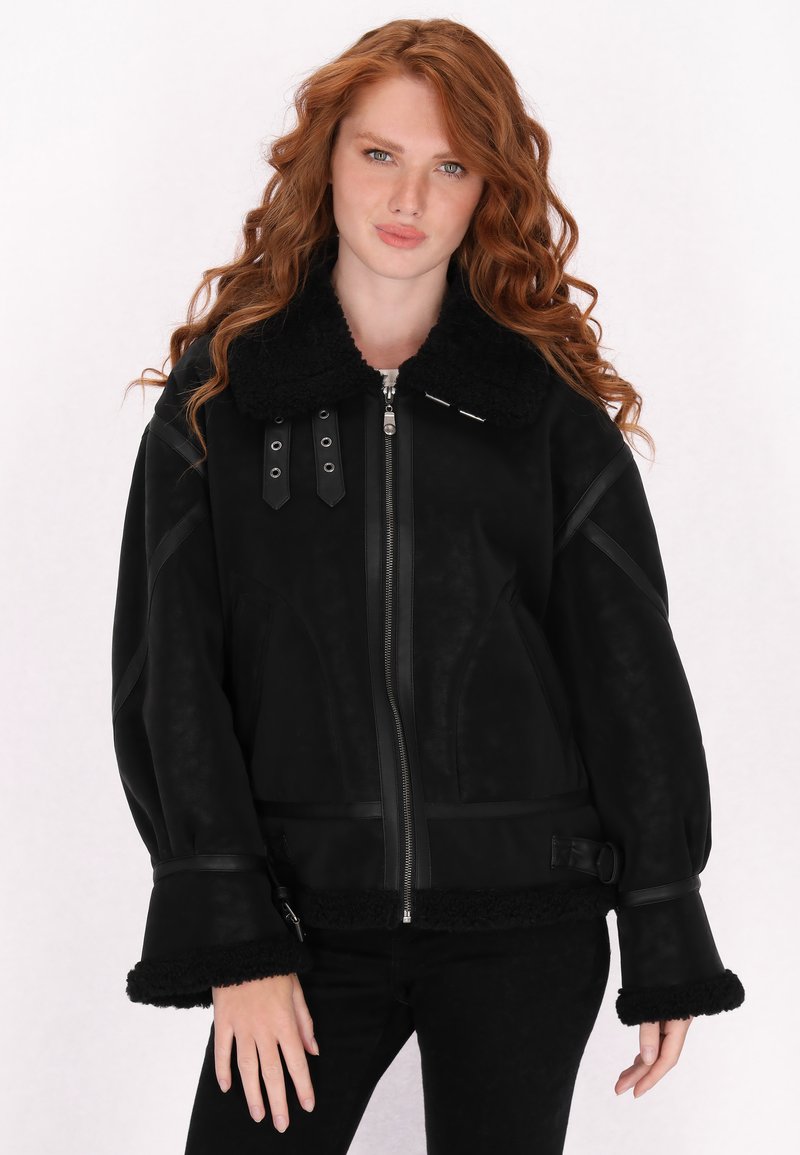 Schwarze Jacke mit einem strukturierten, flauschigen Kragen und Bündchen, ausgestattet mit einem vorderen Reißverschluss und dekorativen Riemen. Glatte Oberfläche und lockere Passform.
