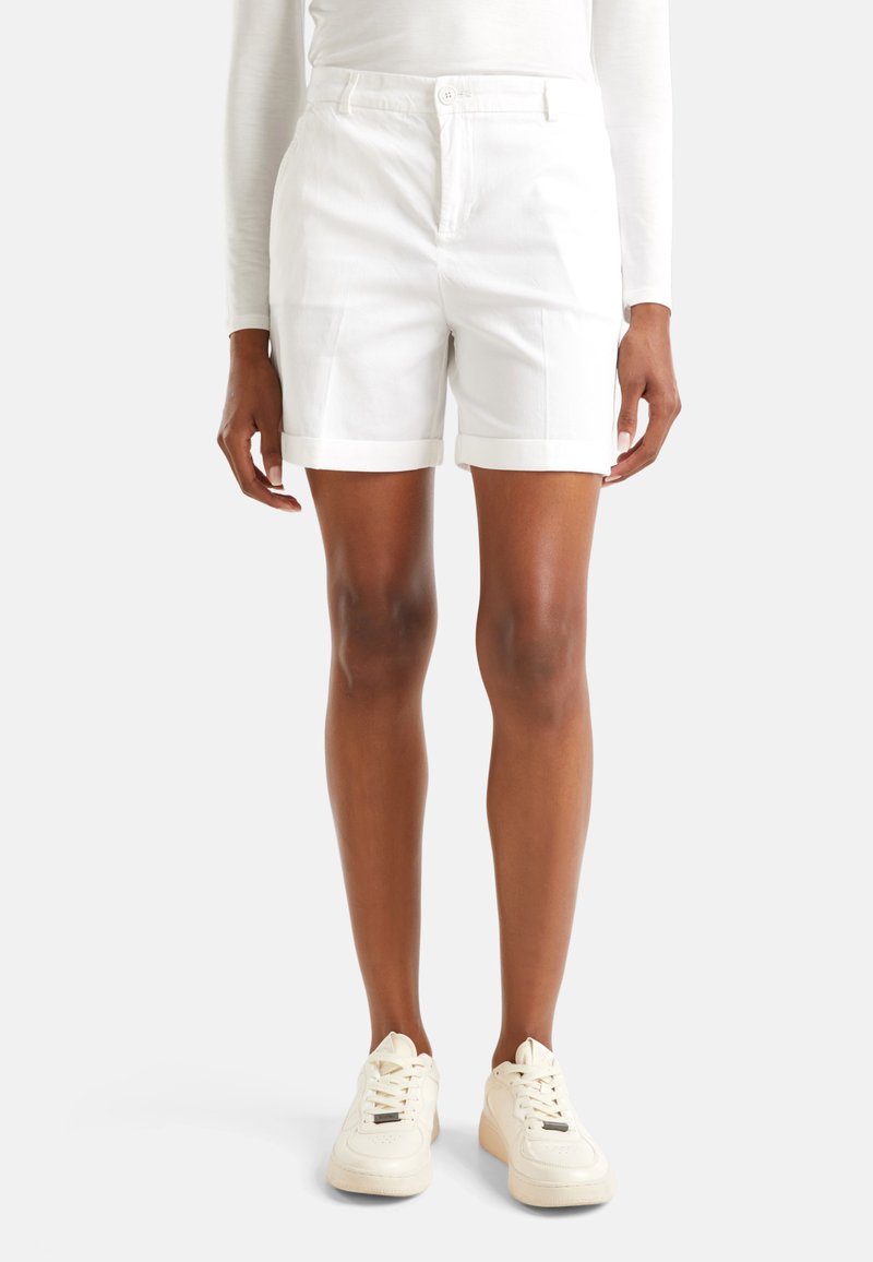 Bílé bavlněné kraťasy s přiléhavým střihem, ohrnutými manžetami a bočními kapsami, doplněné bílými botami na šněrování. Hladká textura.