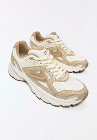 Bež in bele športne superge z mrežastim zgornjim delom, semiš detajli in debelim gumijastim podplatom z vzorcem za oprijem.