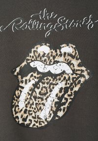 Schwarzes T-Shirt mit einem graphischen Motiv einer braun-beigen Leopardenzungen mit weißen Akzenten. Oben ist der Text "The Rolling Stones" in Schreibschrift zu sehen.