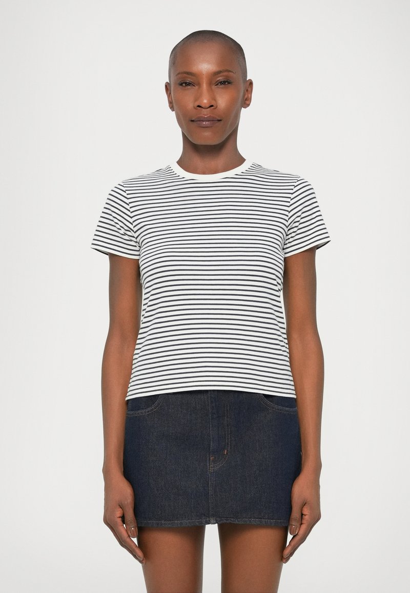 Tricou cu mânecă scurtă în dungi, alb și negru, cu decolteu rotund, din material de bumbac. Asortat cu o fustă mini din denim închis. Design simplu, potrivire lejeră.