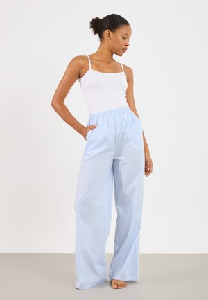 Pantaloni largi, în dungi, de culoare albastru deschis, cu un waistband elastic și buzunare laterale. Asortați cu un top alb, ajustat.