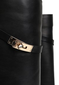 Czarny skórzany produkt o gładkiej fakturze, z pozłacanym zapięciem i detalem paska, podkreślając jego elegancki design.