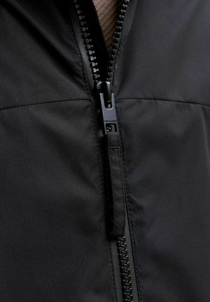 Must tikk-tõmblukuga jakk, millel on stiilne disain, pehme kangapind ja vastupidav tõmblukk kaubamärgiga tõmblukukangiga.