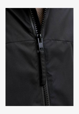 Veste noire zippée présentant un design élégant, une texture de tissu douce et une fermeture éclair durable avec une languette de tirage à logo.