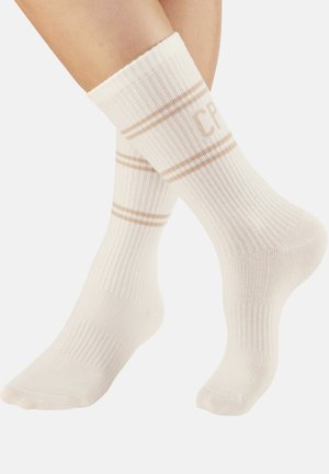 White ribbed socks featuring two tan stripes at the top and "CP" printed in a matching color on the front. Textured knit fabric.