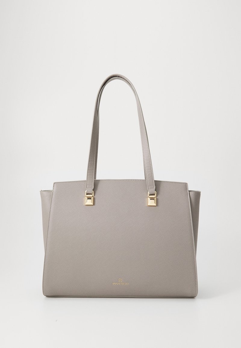 Sac à main en cuir structuré beige avec deux longues poignées et des ferrures dorées, portant la marque Anna Field au centre avant.