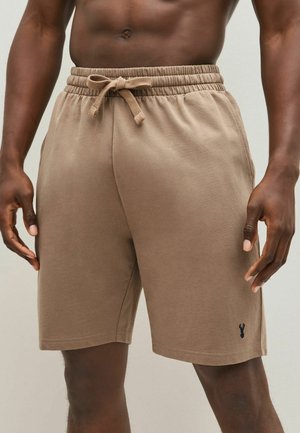 Pantalones cortos de mezcla de algodón marrón con una cinturilla elástica y cordón. Bolsillos laterales y un pequeño logotipo en el dobladillo izquierdo. Textura suave.