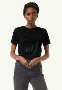 Czarny t-shirt z krótkim rękawem o fakturowanym wzorze, z błyszczącymi akcentami z przodu i okrągłym dekoltem, w połączeniu z szarymi dżinsami.