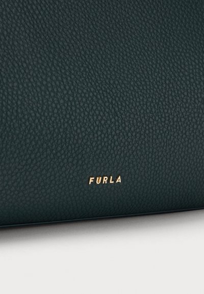Тъмнозелена текстурирана кожена повърхност с малко златно лого на марката Furla, разположено централно близо до долния ръб.