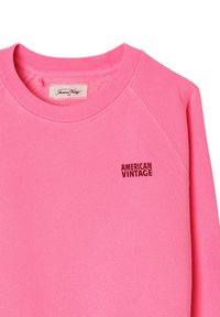 Knallpinkes Sweatshirt mit Rundhalsausschnitt und "AMERICAN VINTAGE" Schriftzug in kleinen schwarzen Buchstaben auf der oberen linken Brust.