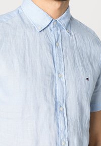 Lichtblauw linnen overhemd met korte mouwen en een button-down kraag, voorzien van een klein logo op de borst en een gestructureerde stofafwerking.