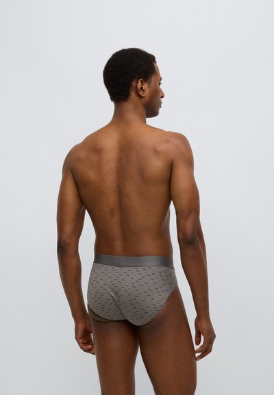 Γκρι μπριζμαδάκια από απαλό ύφασμα με διακριτικό σχέδιο. Διαθέτουν παχύ, ελαστικό ζωνάρι και άνετη εφαρμογή. Η οπισθία όψη δείχνει αδιάκοπο σχέδιο.