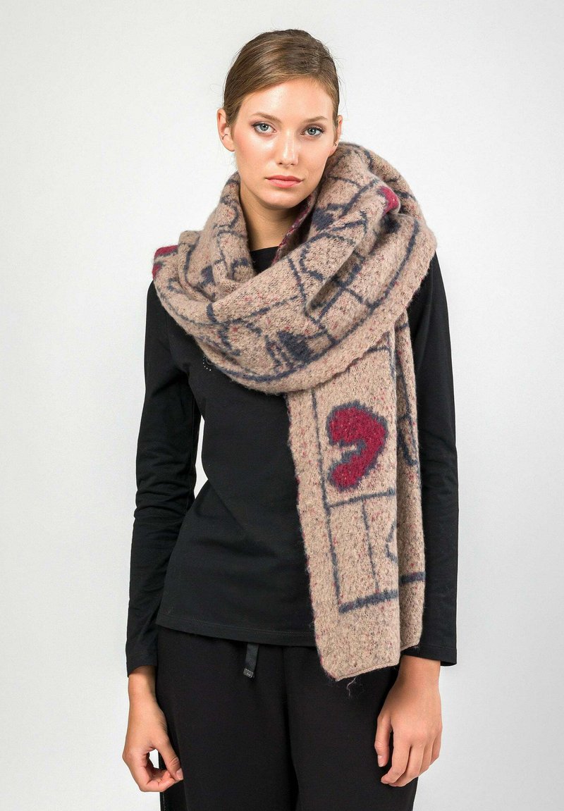 Sciarpa di lana beige con una texture morbida e pelosa e motivi astratti rossi e blu scuro. Indossata sciolta intorno al collo.