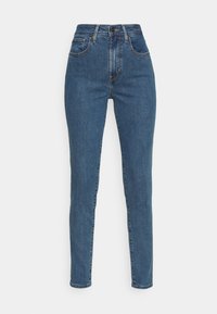 Jeans ajustados en denim azul medio, de cintura alta con cinco bolsillos, costuras visibles y cremallera. Textura suave, diseño clásico.