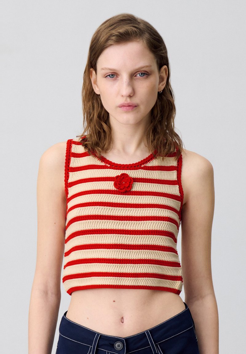 Top corto all'uncinetto con strisce orizzontali rosse e beige, scollo rotondo e un accento floreale 3D sul petto.